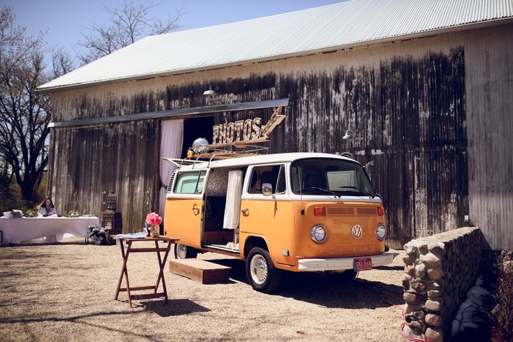 an orange and white van parked in front of a barn