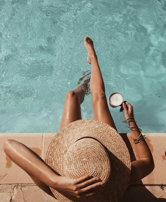 a woman laying on the side of a swimming pool with her feet up in the air