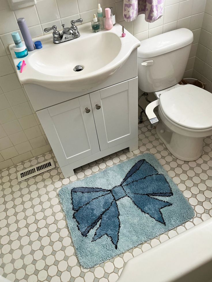 a bathroom with a blue rug on the floor next to a white toilet and sink