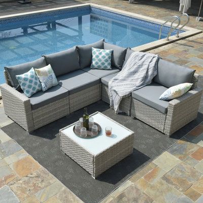 an outdoor sectional set next to a swimming pool with pillows and throw pillows on it