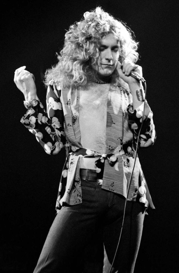 a man with long hair standing on stage holding a microphone