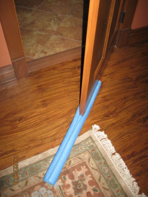 an open door with a blue handle on the floor next to a rug and mirror