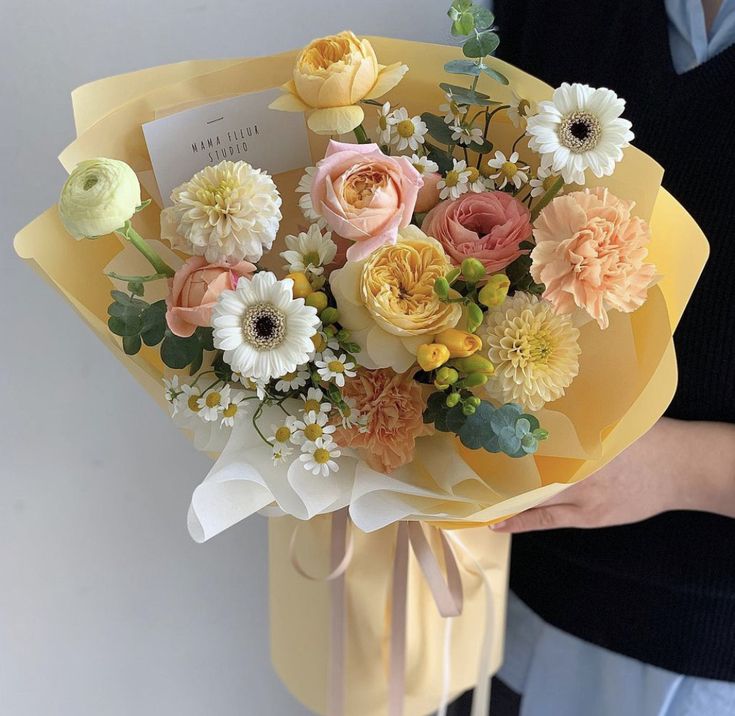 a woman holding a bouquet of flowers in her hand with a note attached to it