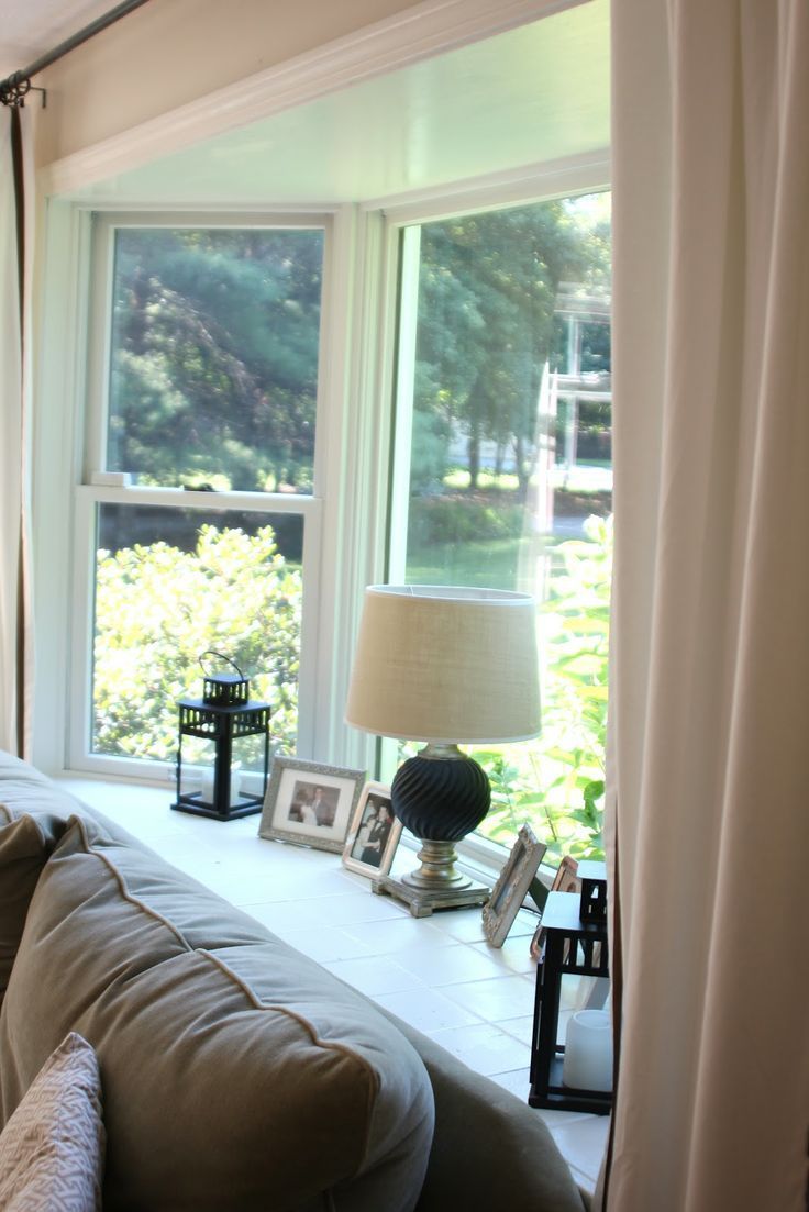 a living room filled with furniture and a lamp on top of a window sill