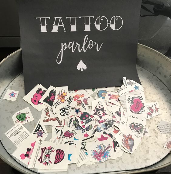 tattoo parlor sign surrounded by lots of stickers on a metal tray in front of an oven