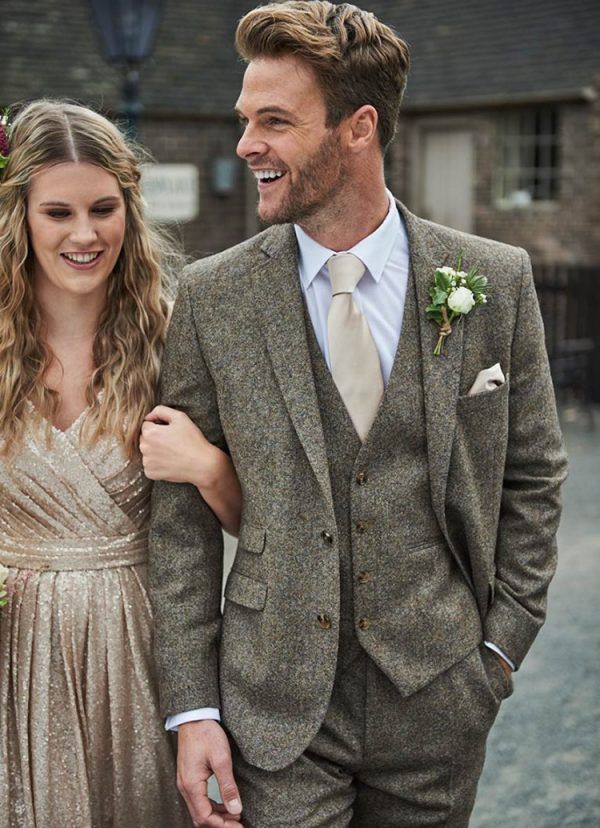 a man in a suit and tie standing next to a woman wearing a gold dress