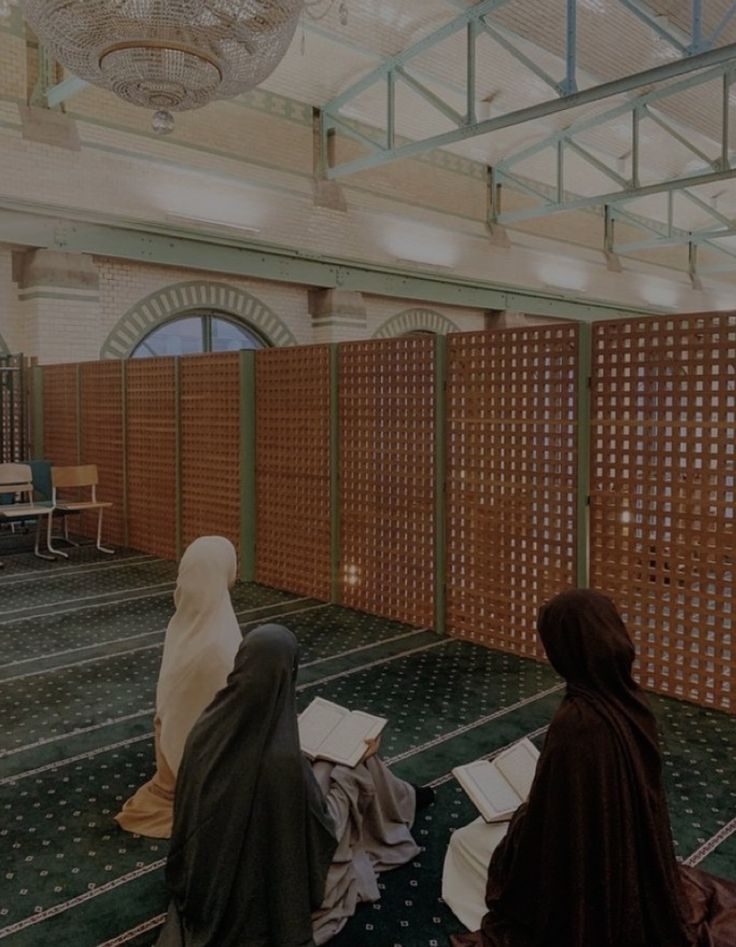 two women sitting on the floor in a room with wooden partitions and green carpet