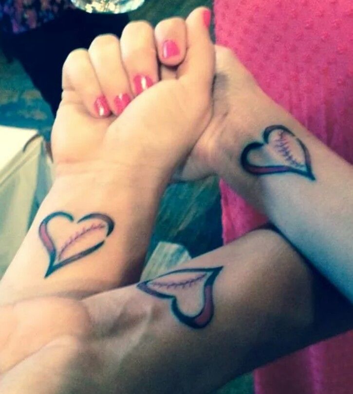 two people holding hands with tattoos on their arms and one has a baseball mitt in the shape of a heart