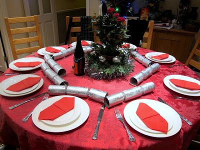 the table is set for christmas dinner with red and white place mats, silverware, napkins, wine bottle