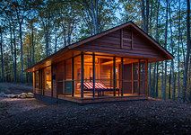 a small wooden cabin in the woods at night