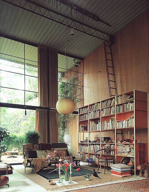 a living room filled with lots of furniture and bookshelves next to large windows