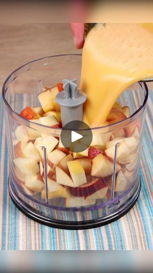 someone pouring cheese into a food processor filled with apples and other fruit ingredients to make a smoothie