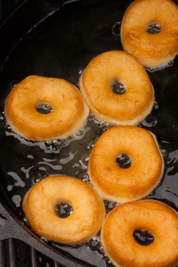 four donuts frying in oil on a pan