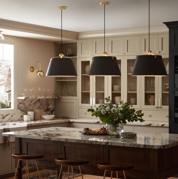 a kitchen with marble counter tops and pendant lights