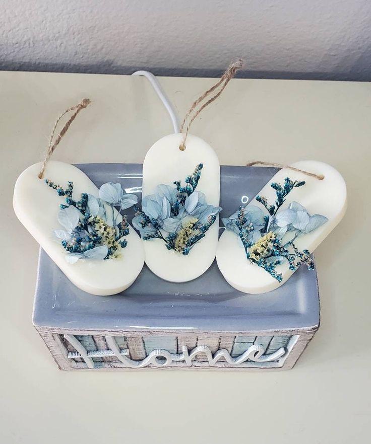 three white ceramic pieces with blue flowers on them sitting on a table next to a box