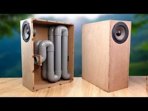 two speakers sitting on top of a wooden box next to each other with pipes coming out of them