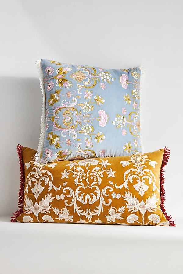 two decorative pillows sitting on top of a white shelf next to each other in front of a wall