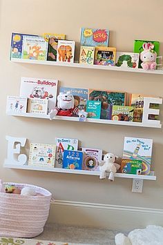 two white bookshelves with children's books on them in a child's room