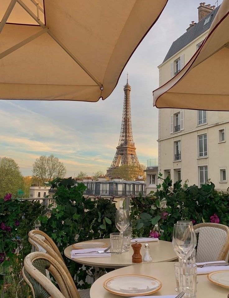 an outdoor dining area with tables and chairs, overlooking the eiffel tower in paris