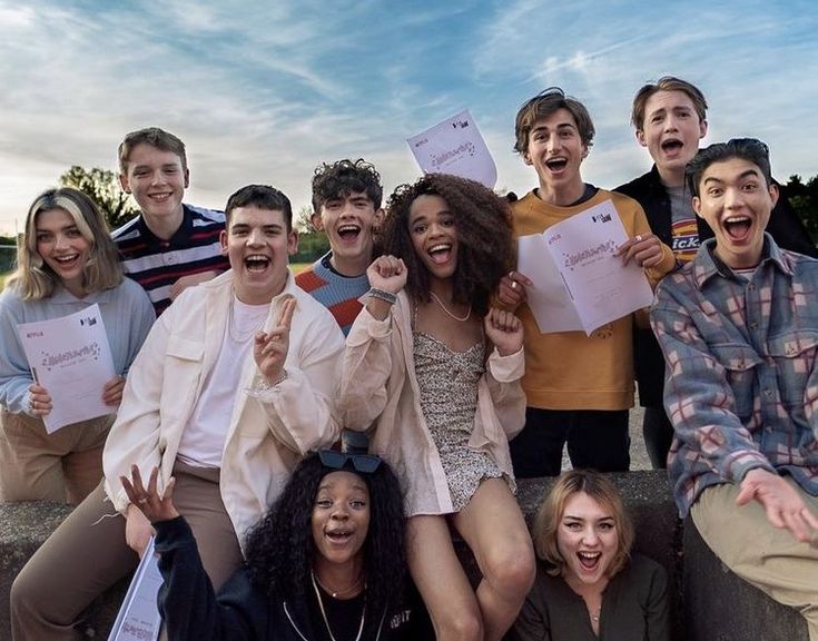 a group of young people standing next to each other holding up papers and making funny faces