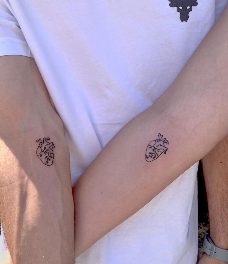 two people holding each other with tattoos on their arms