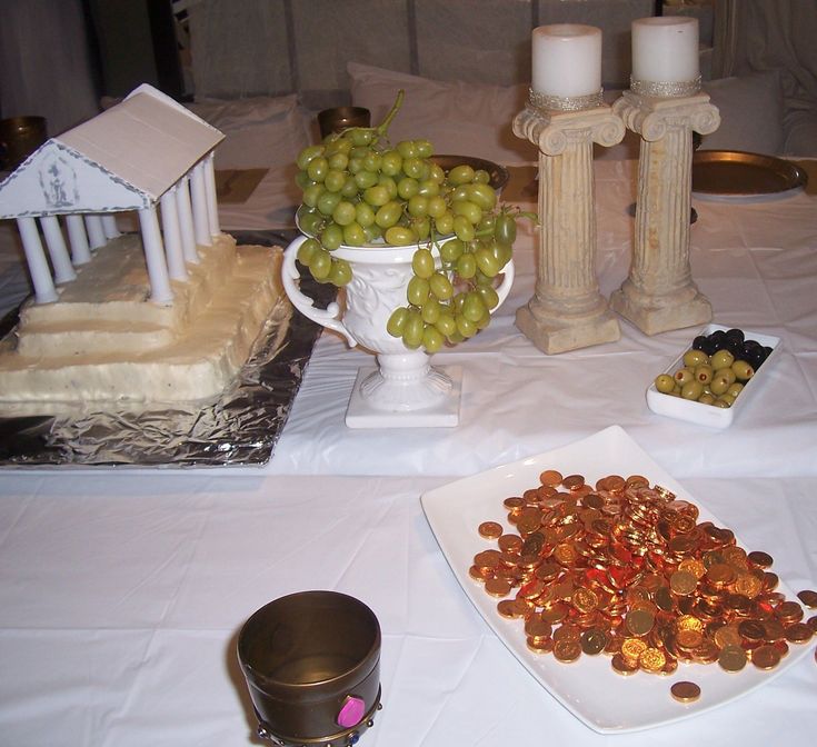 grapes and nuts on a table in front of a small model house, candles and other decorations