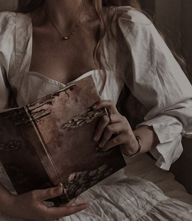 a woman sitting on a bed holding a book