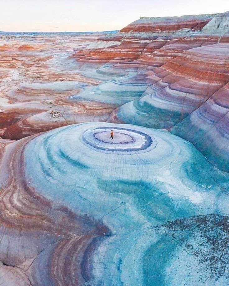 a person standing in the middle of a large area with blue and red rocks on it