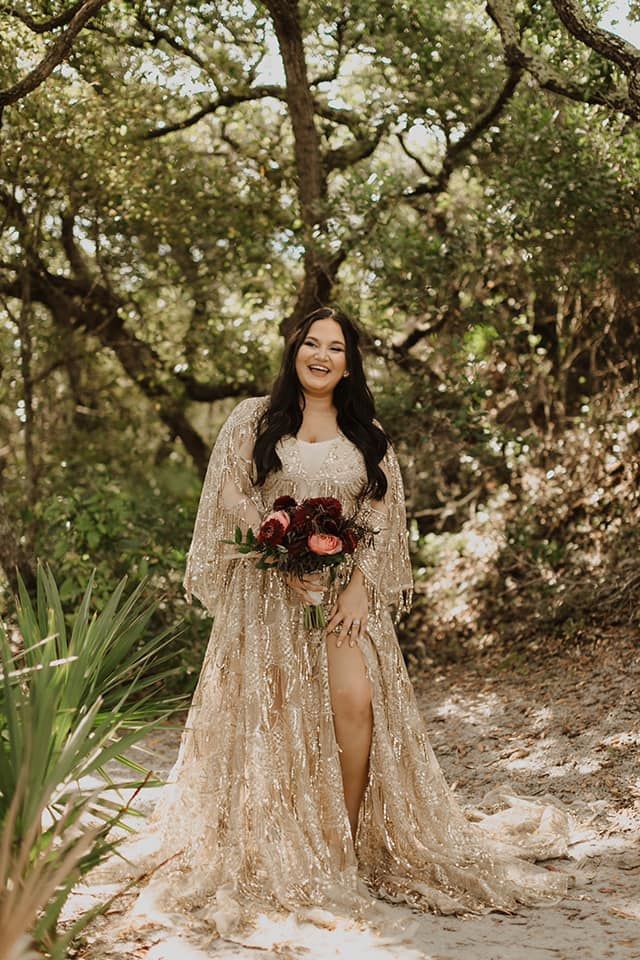 a woman in a long dress standing under trees