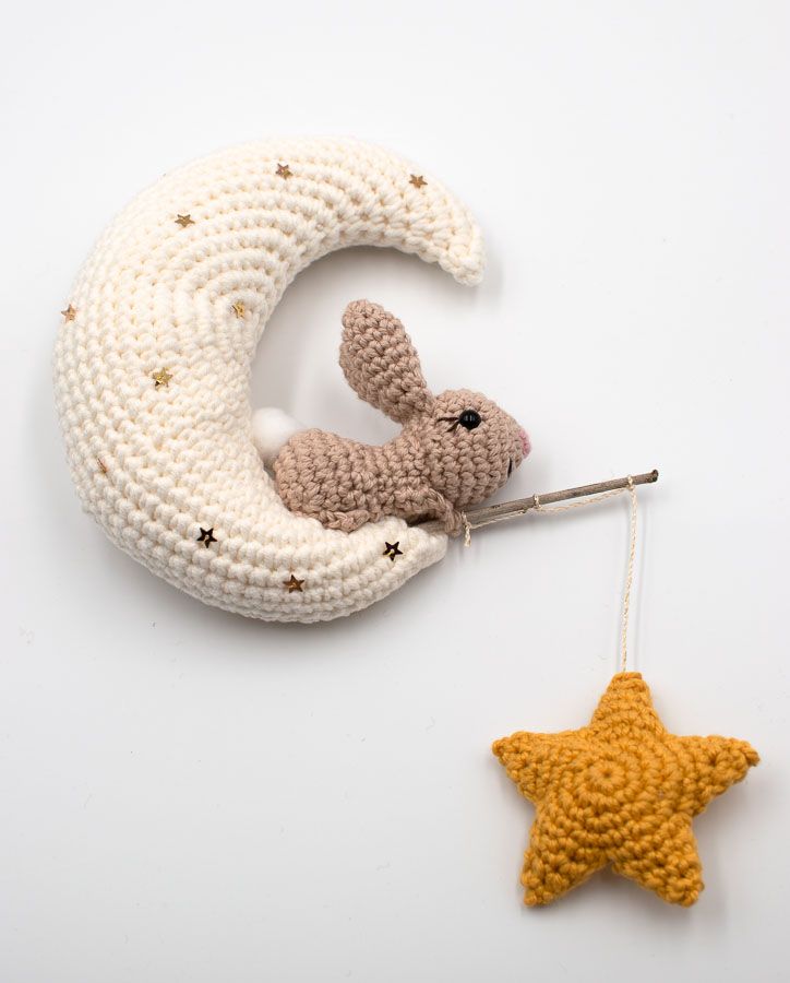 a crocheted stuffed animal sitting on top of a crescent next to a star ornament