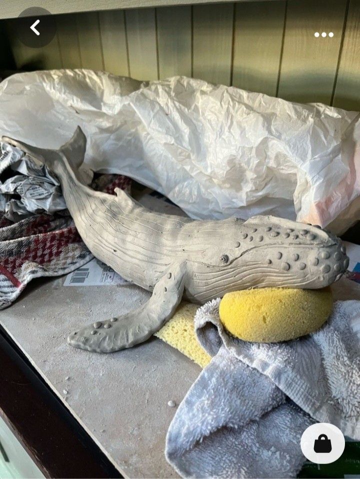 a stuffed whale laying on top of a counter next to a pile of cloths