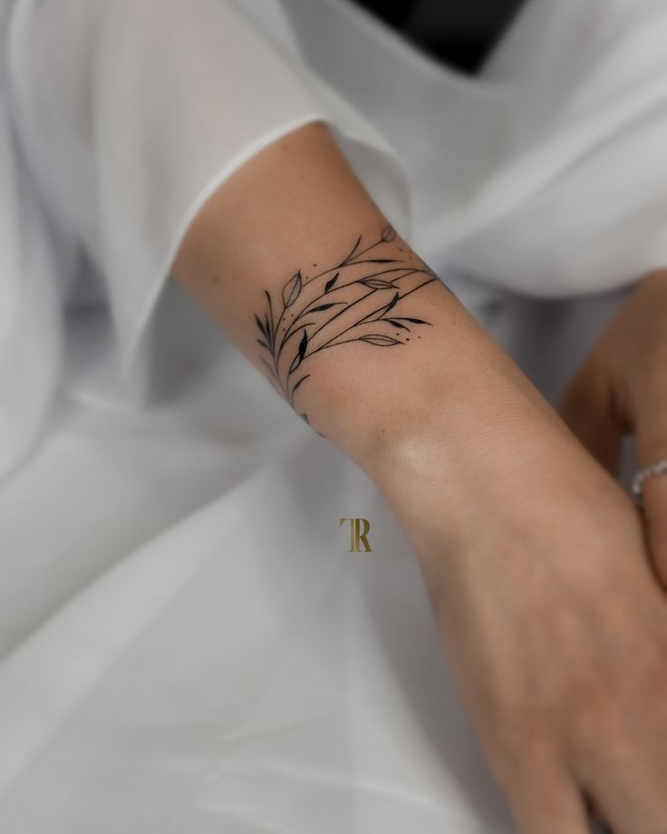 a woman's arm with a small tattoo on her left wrist and the word ir written in gold