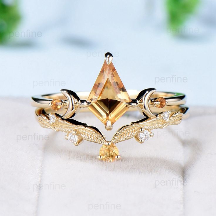 a yellow diamond ring sitting on top of a white surface with leaves and diamonds around it