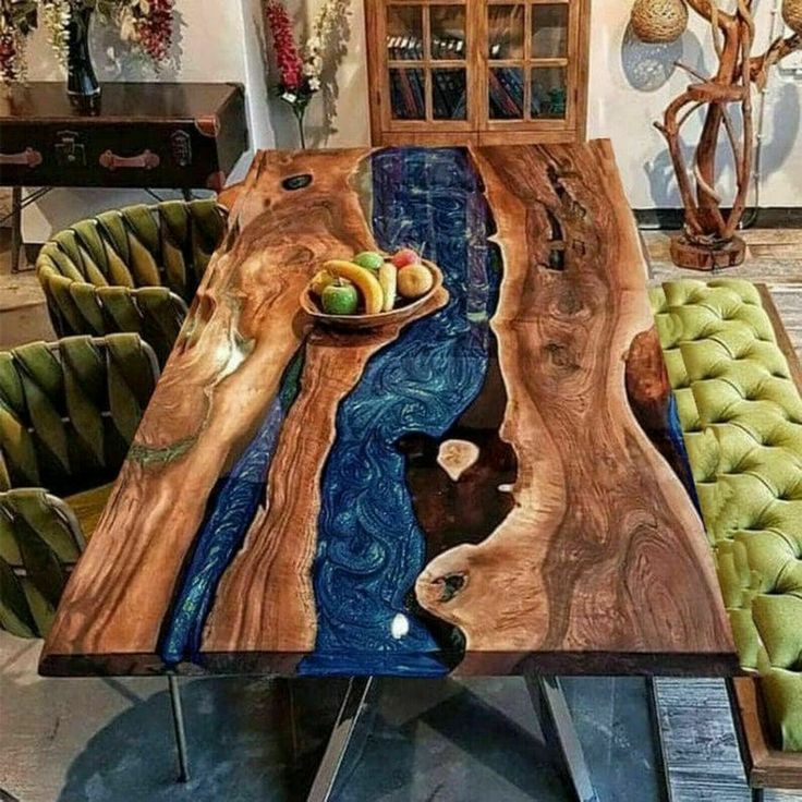 the table is made out of wood and has green velvet chairs around it, along with a bowl of fruit