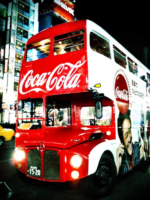 a double decker bus with coca cola advertisement on it's side in the city