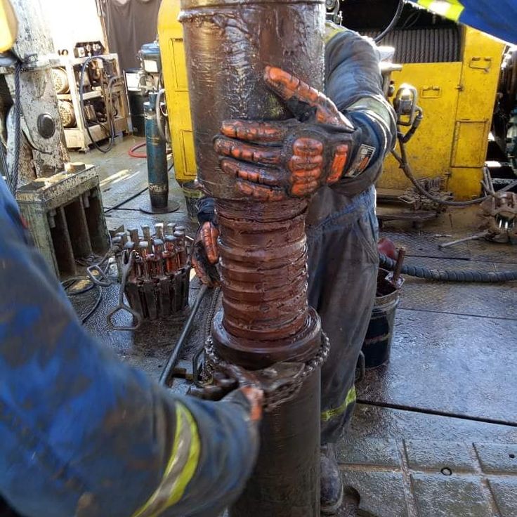 a man working on a large pipe in a factory with lots of machinery behind him