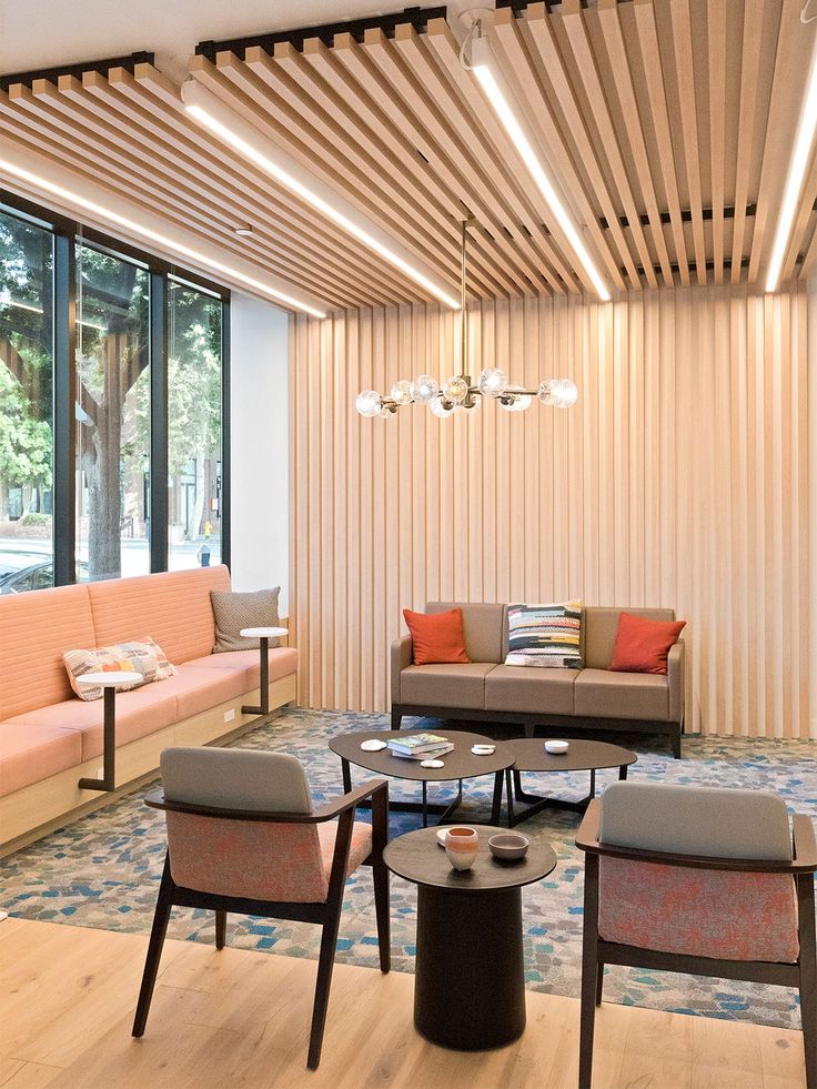 a living room filled with lots of furniture next to a large glass window covered in wood slats