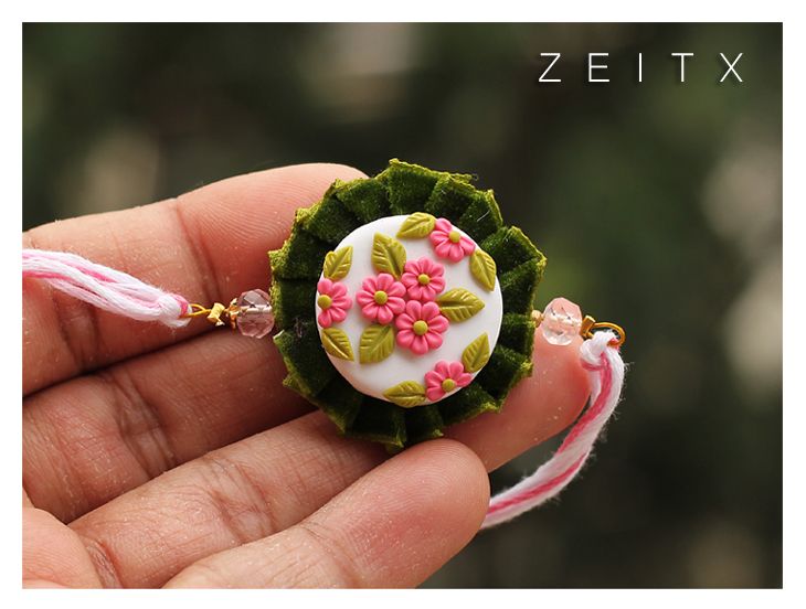 a hand holding a small white and pink flower brooch with green leaves on it