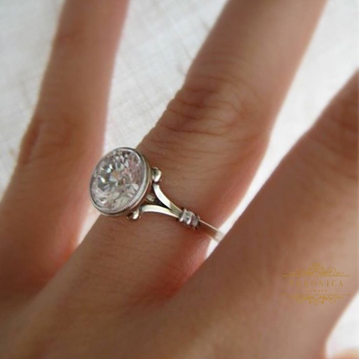 a close up of a person's hand with a diamond ring on their finger