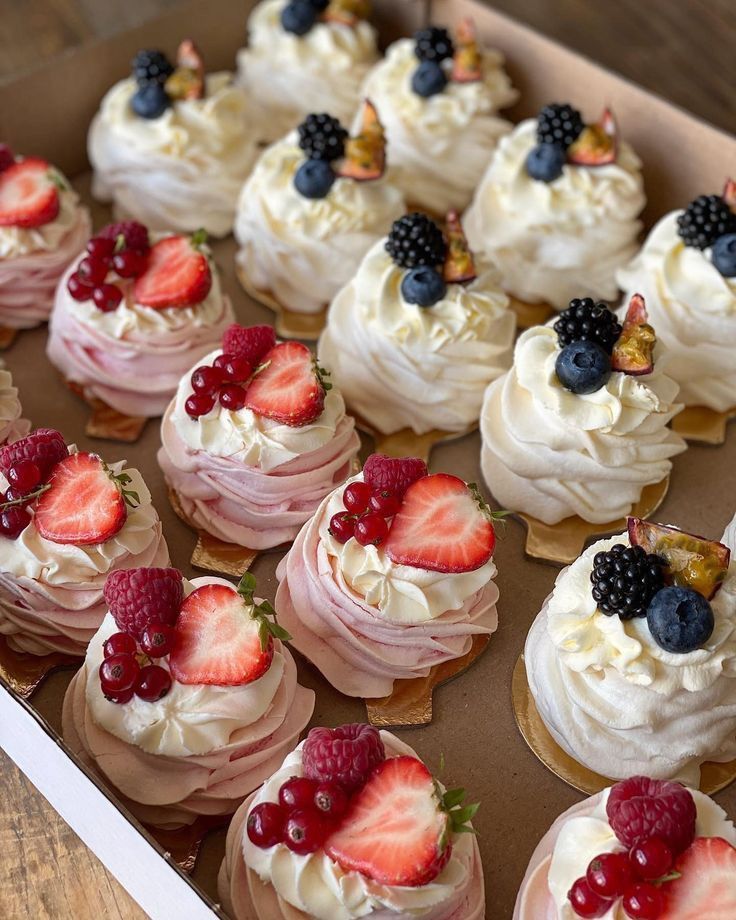 a box filled with cupcakes covered in frosting and topped with fresh berries