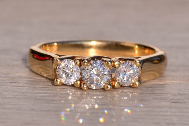 three stone diamond ring sitting on top of a wooden table