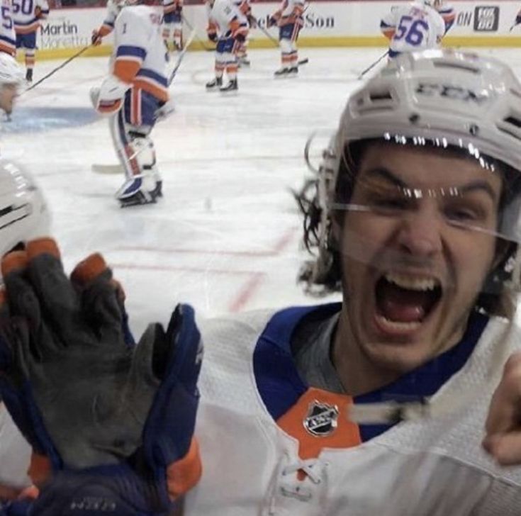 a hockey player holding his hands up in the air with an excited look on his face