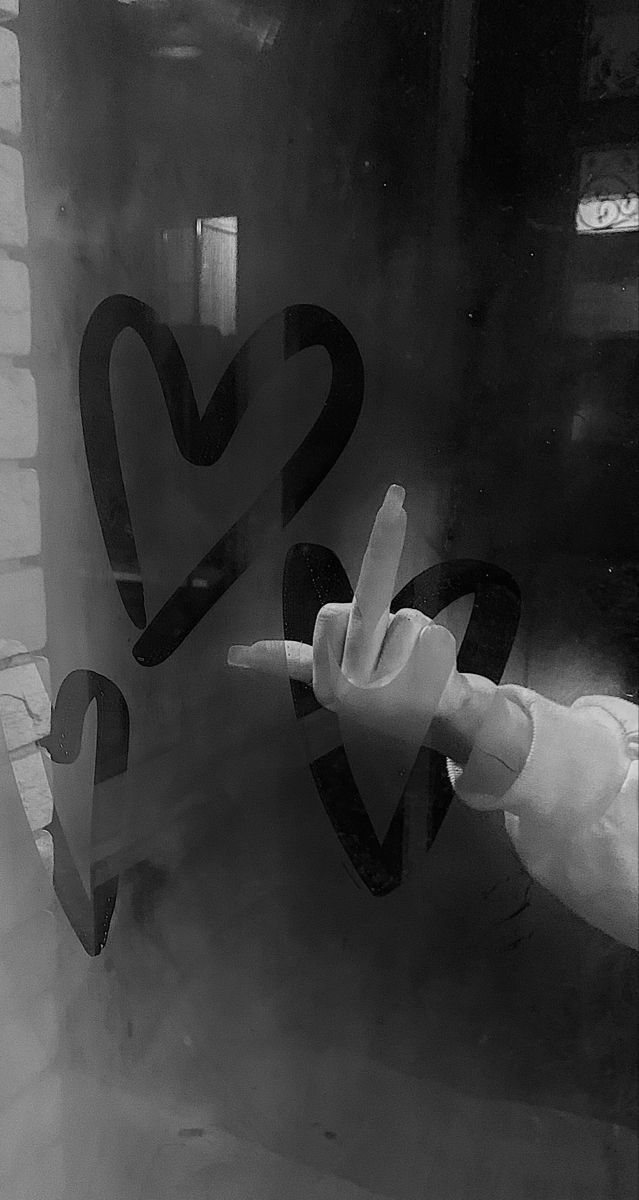 the hand is pointing at two heart shaped stickers on the glass window sill