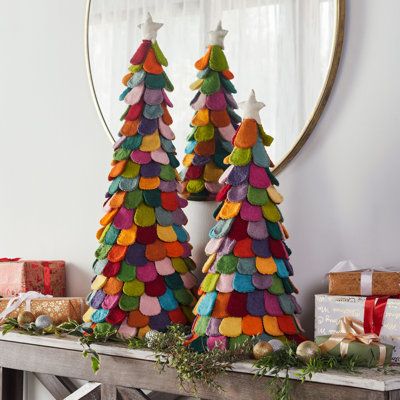 two christmas trees made out of felt sitting on top of a wooden table in front of a mirror