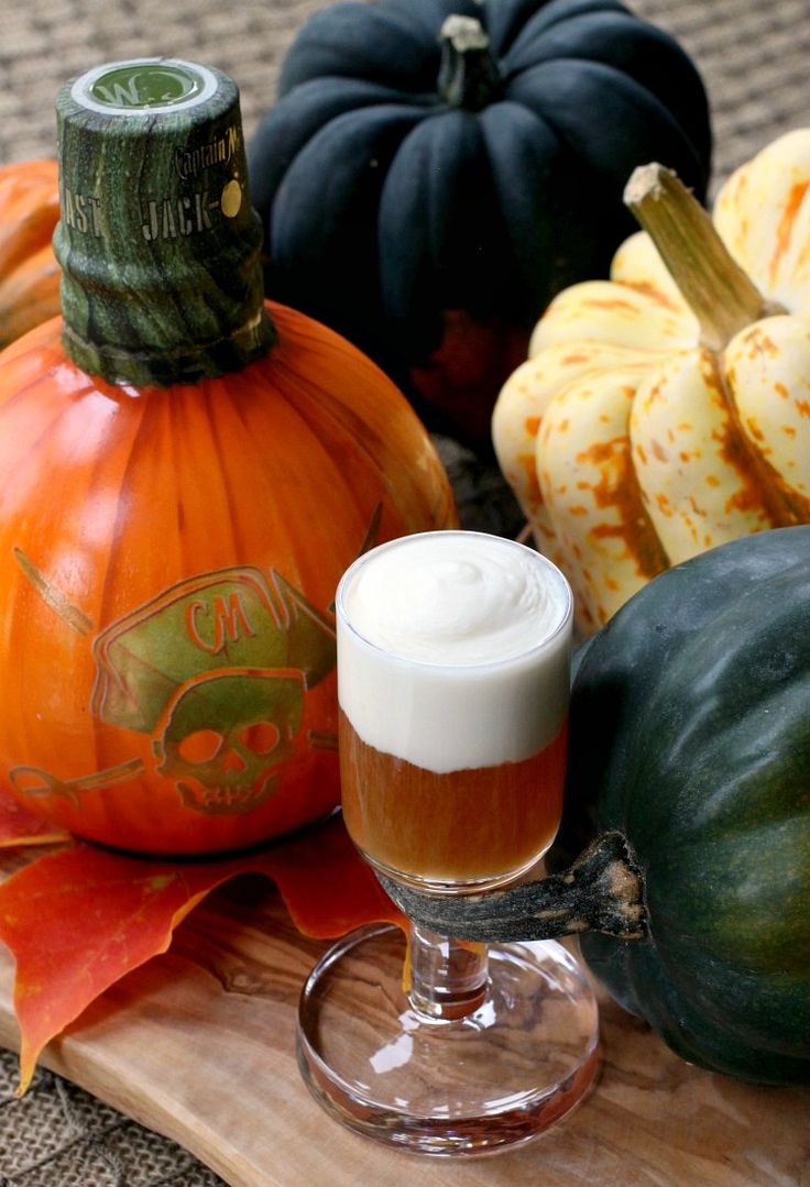 a glass of beer sitting on top of a wooden tray next to pumpkins and gourds