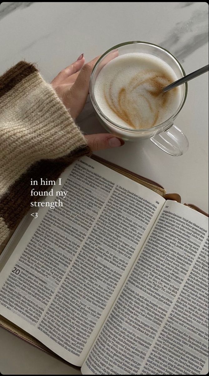 an open book sitting on top of a table next to a cup of coffee