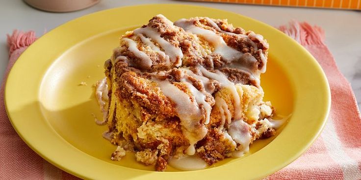 a yellow plate topped with a piece of cinnamon roll covered in icing and drizzled