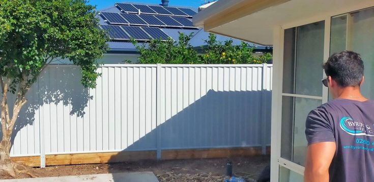 a man standing in front of a house with a solar panel on top of it