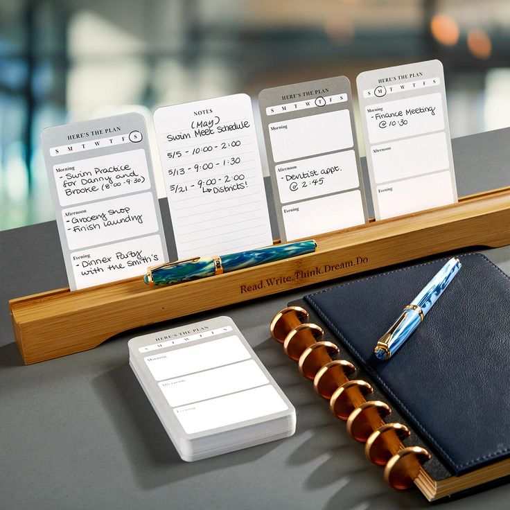 notepads and pen sitting on top of a desk next to a wooden stand