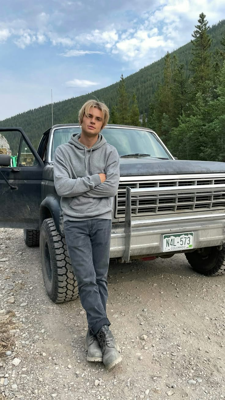 a man standing in front of a truck with his arms crossed and looking at the camera